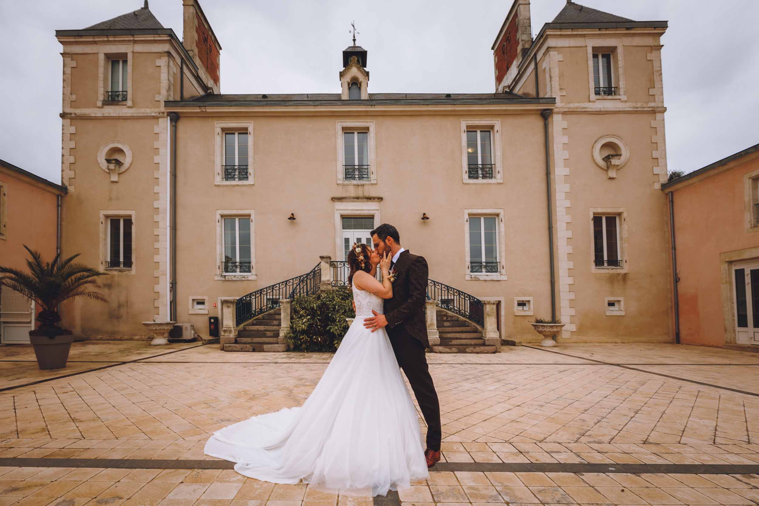 Les mariés s'embrassent da=evant le château en Vendée