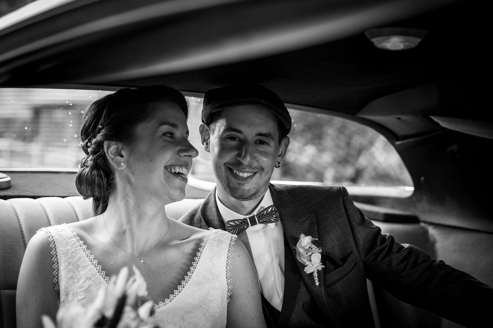 Les mariés rient dans la voiture pour leurs photos de mariage à Fontenay le Comte en Vendée