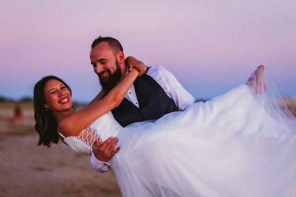 Le marié tient la mariée dans les bras sur une plage de Vendée