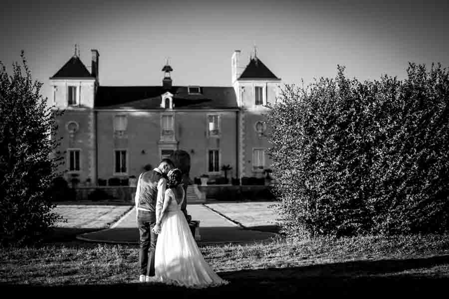 Les mariés s'embrassent devant le château pour leur mariage en Vendée