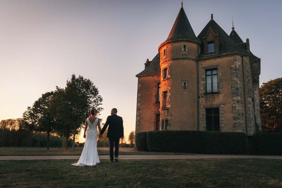 Photographie d'un Photographe de Mariage montrant un couple qui marche près d'un château lors d'un mariage en Vendée