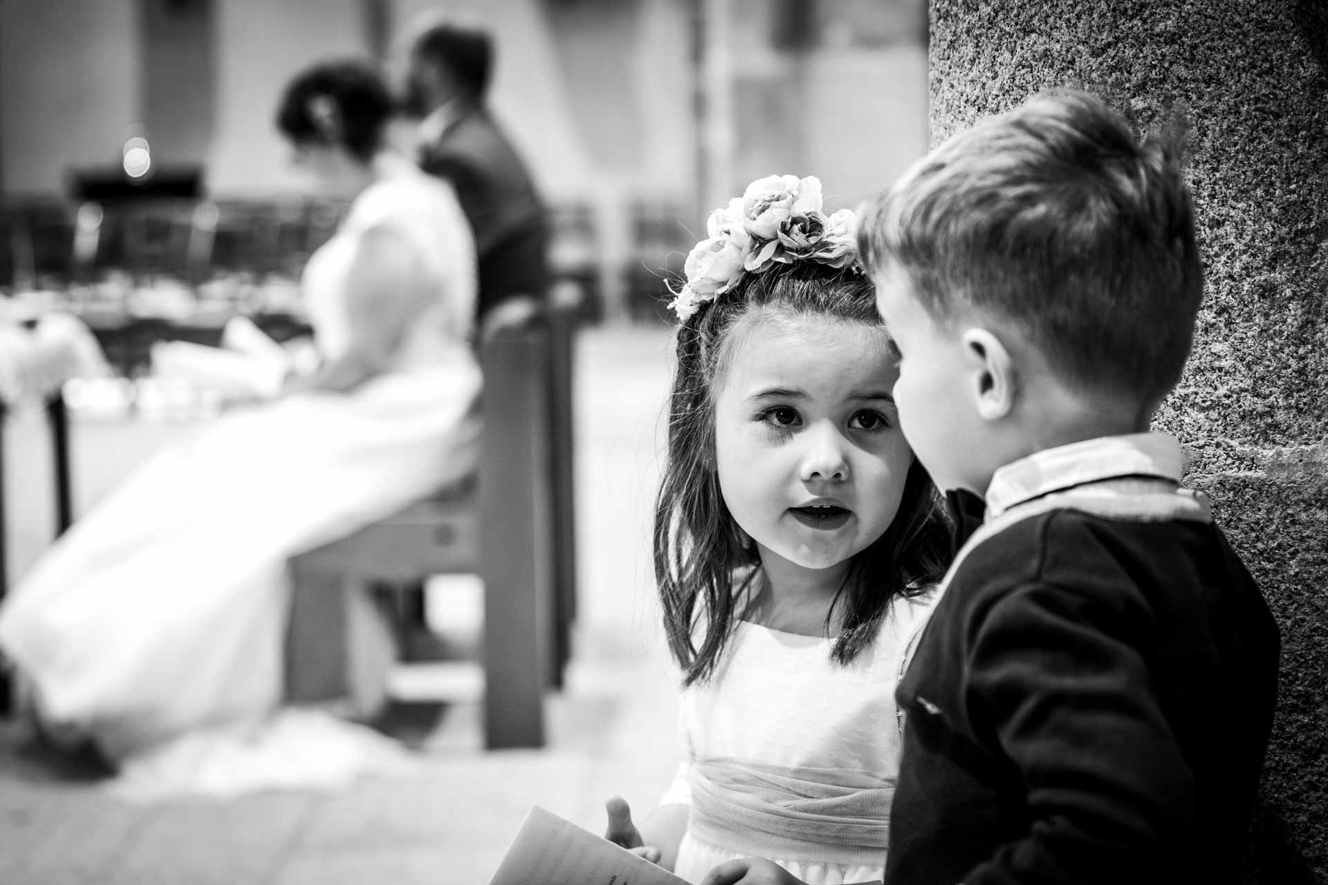 Photographie d'un Photographe de Mariage montrant des enfants qui chuchotent dans une église lors d'une cérémonie en Vendée