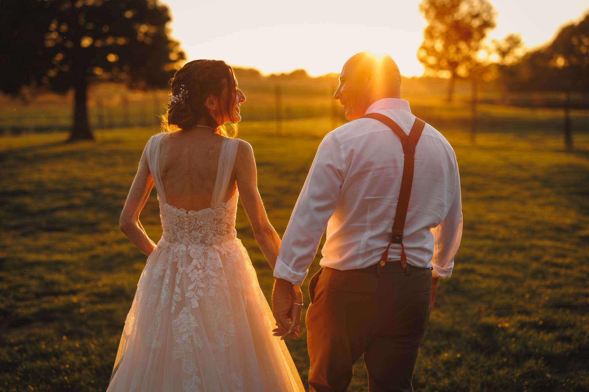 Photographie d'un Photographe de Mariage montrant les mariés qui se tiennent par la main au coucher du soleil pour leur mariage à La Roche sur Yon