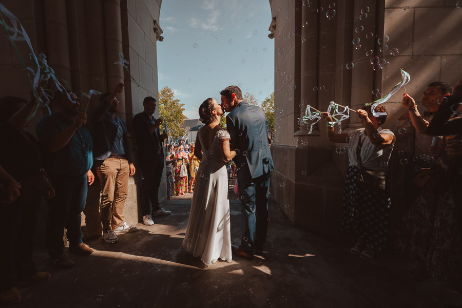 Photographie d'un Photographe de Mariage montrant les mariés qui s'embrassent à la sortie de l'église pour leur Mariage à la Rochelle