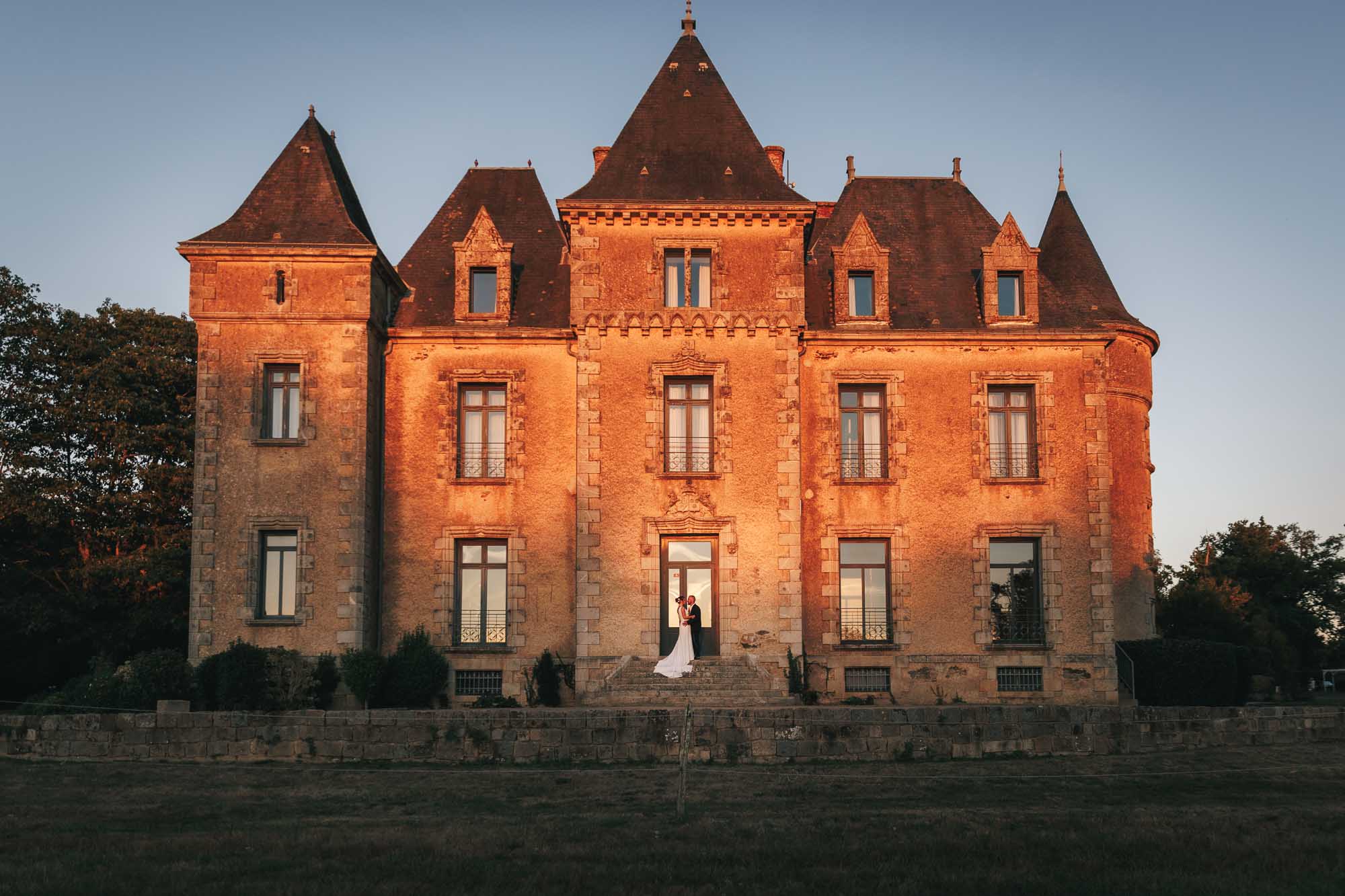 Photographie d'un Photographe de Mariage qui montre des mariés qui posent devant un château lors de leur mariage à Nantes