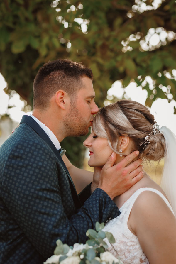 Photographie d'un Photographe de mariage montrant le marié qui embrasse la mariée pour leur mariage en Vendée