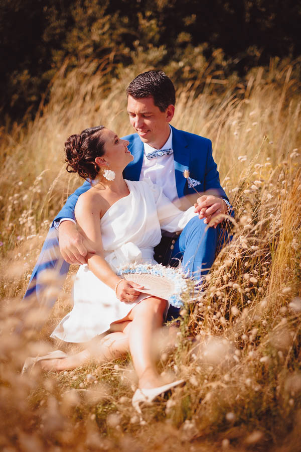 Photographie d'un photographe de mariage montrant des mariés assis dans un champ lors d'un mariage en Vendée