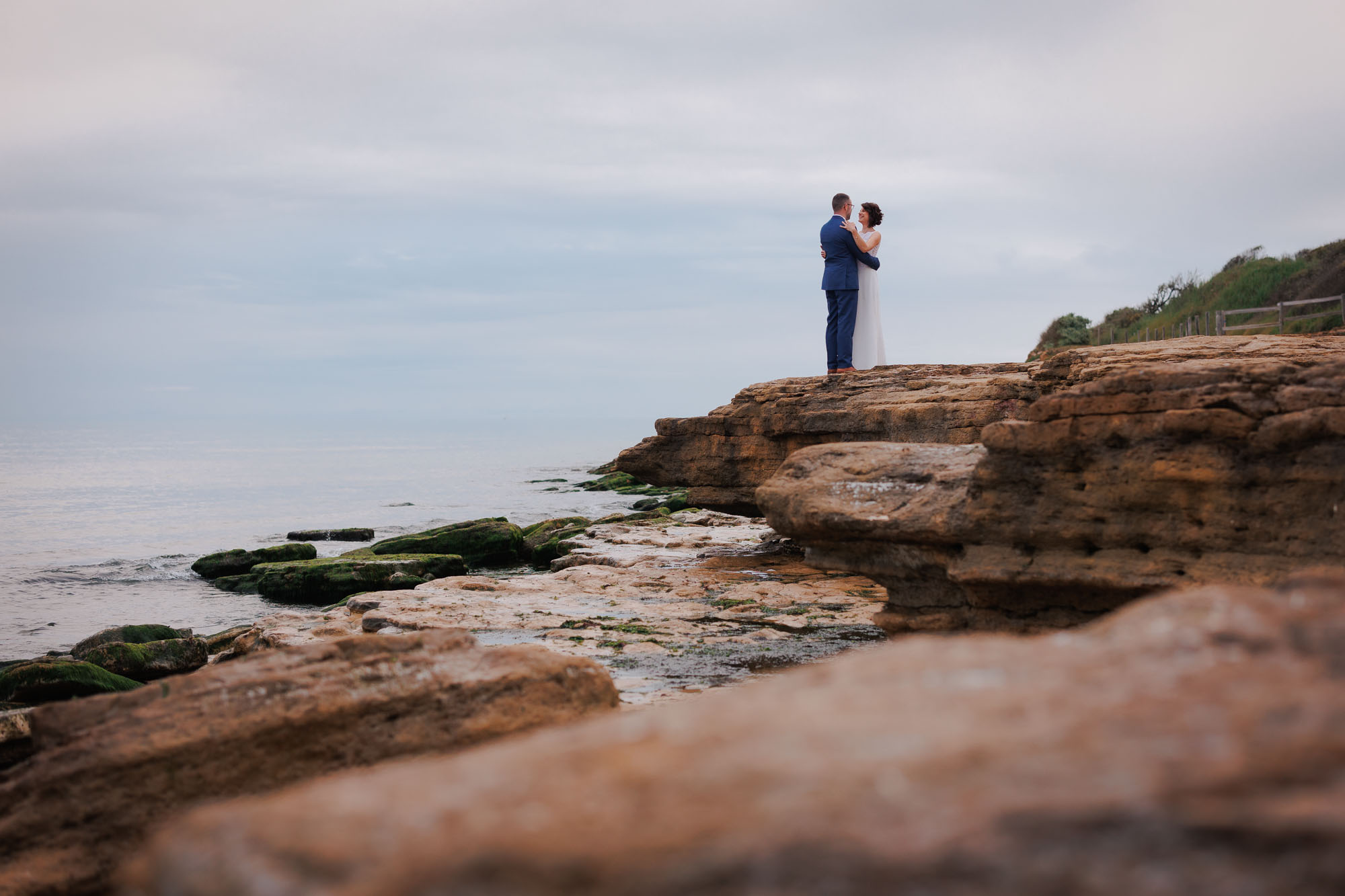 Les mariés se tiennent dans les bras sur les rochers pour leur séance de photos de couple de mariage