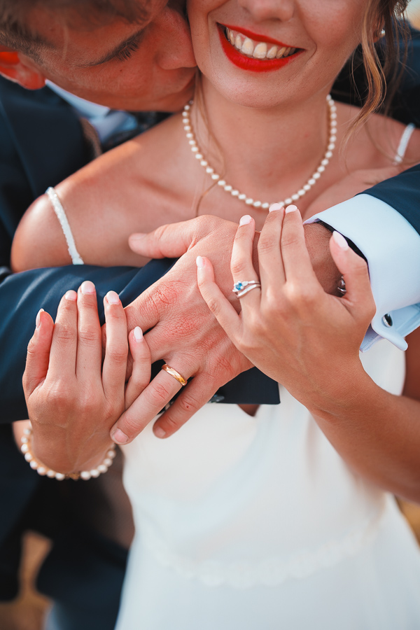 Les mariés se tiennent les mains et montrent leur alliances pour la séance photo de leur photographe de mariage, en Vendée