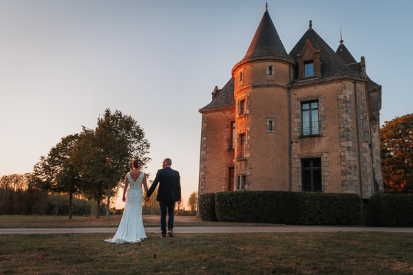 Les mariés marchent vers un beau château du Domaine de Brandois (Vendée), Photographie d'un photographe de mariage professionnel